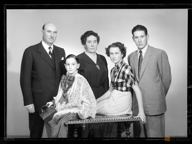 Retrato en plano americano de una familia seria formada por una pareja de mediana edad, un hombre y una mujer jóvenes y una niña